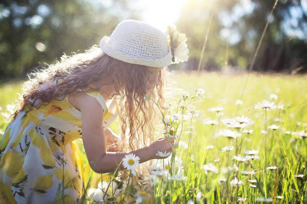 A young girl smelling a flower in a field of wildflowers