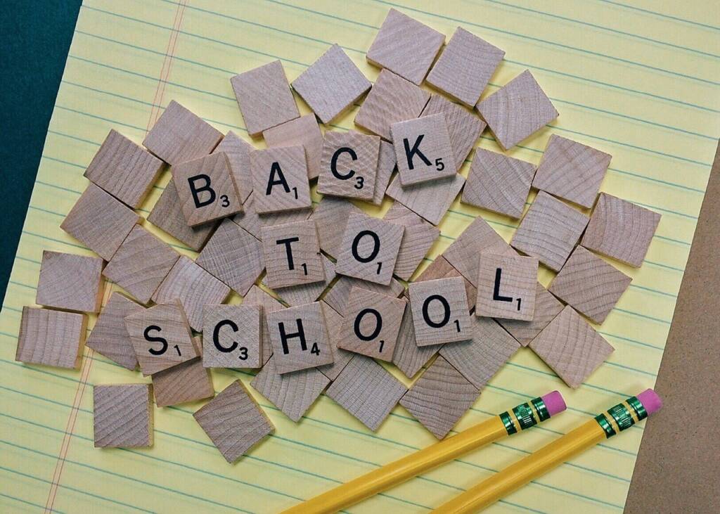 Back to School spelled out with Scrabble tiles on a sheet of paper with two pencils.