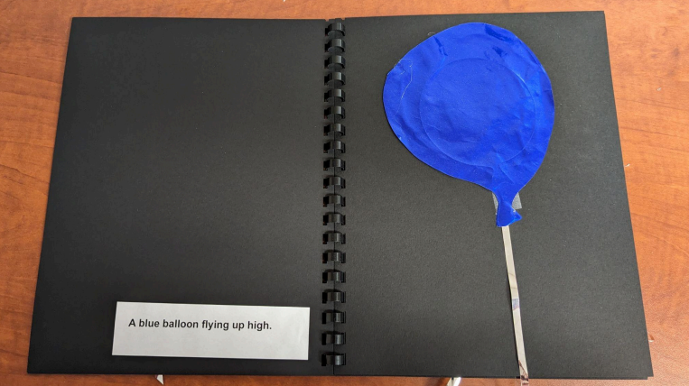 Balloon book page with a balloon and a sentence that states, "A blue balloon flying up high."