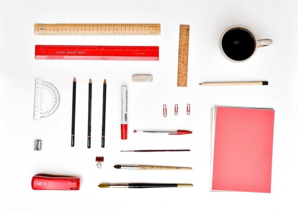 Organized desk top with pencils, paper, brushes, stapler, and other items in neat rows.