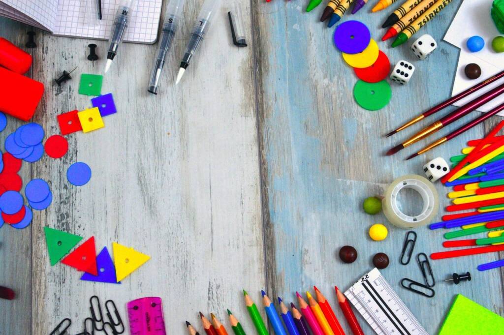 An array of supplies that include colored pencils, paperclips, crayons, and other school items. 