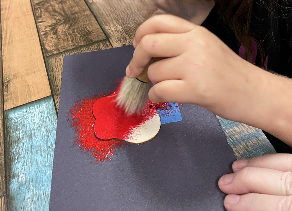 Student painting a wooden apple red.