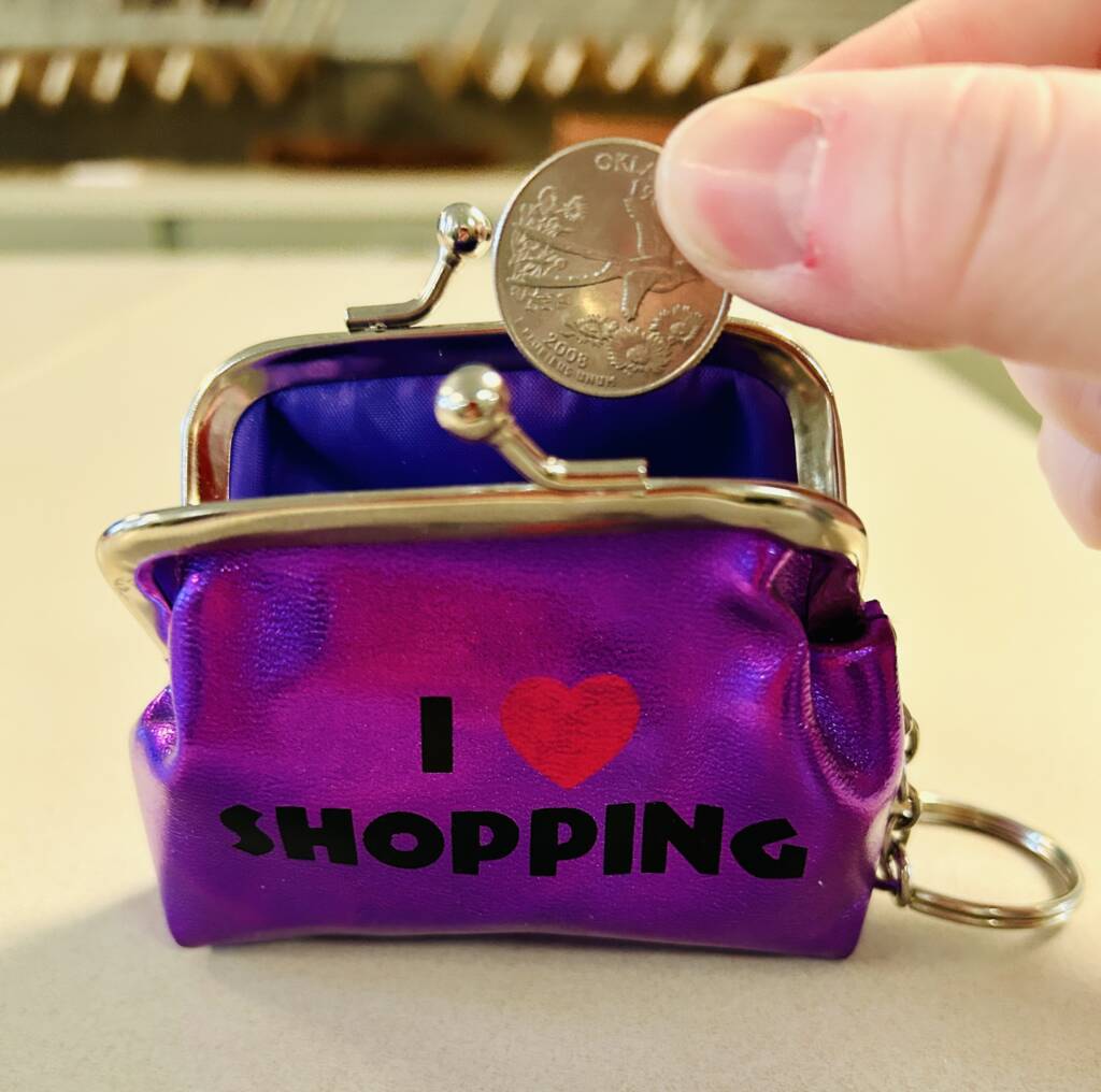 Small coin purse with a hand putting a coin in it.