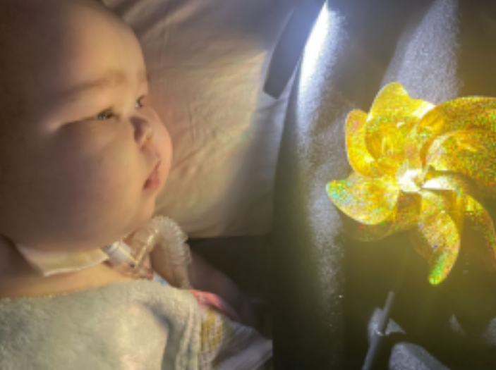 Baby Caroline looking at the golden pinwheel.