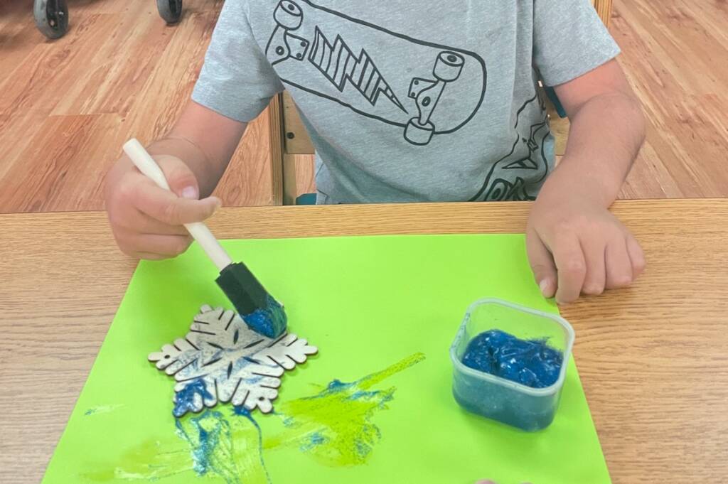 student painting a wooden snowflake