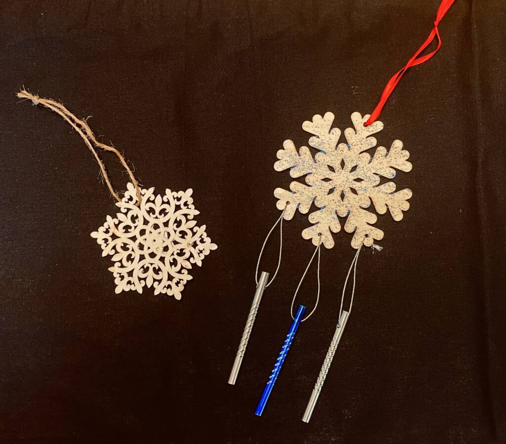 Two wooden snowflake wind chimes with ribbon to hang them up.