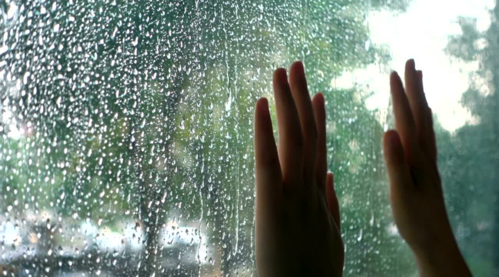 Hands on a window with a rainy day