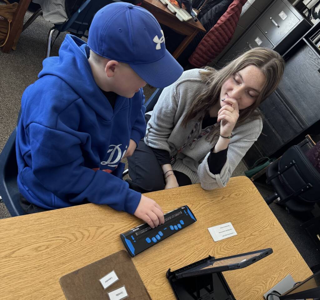 Liam at school with a teacher using the ipad with refreshable braille. 